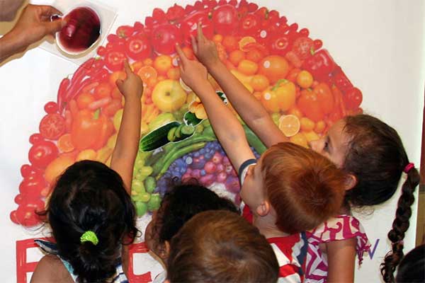 Children pointing at fruits and vegetables.